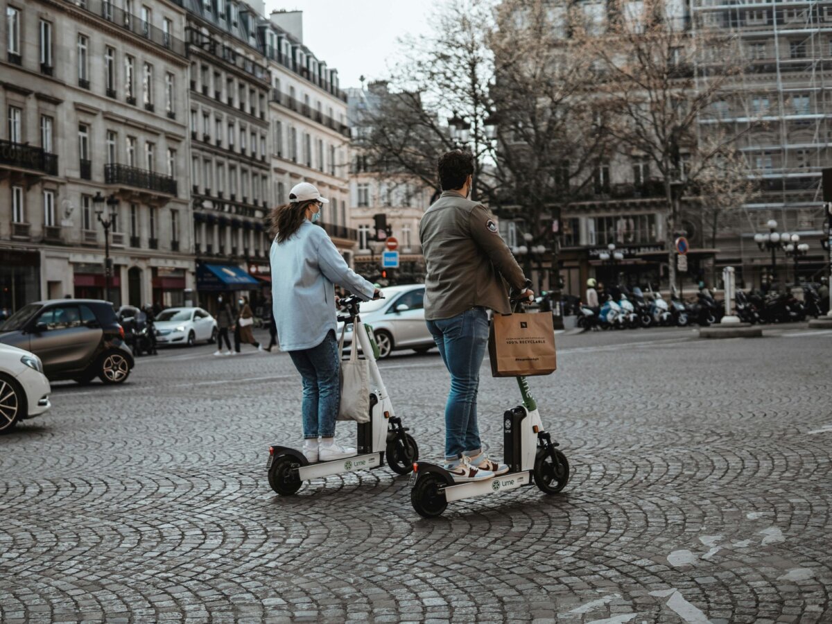 Two people in a city riding electric scooters
